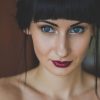 a woman with blue eyes and red lipstick testimonials